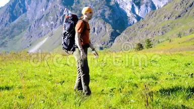 徒步旅行者带着背包在绿色的山地草地上行走。 夏季运动和娱乐理念。